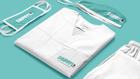 The clean and professional brand identity we designed for wellness company Drippyl, showcased on a set of medical scrubs, a cap, and a face mask.